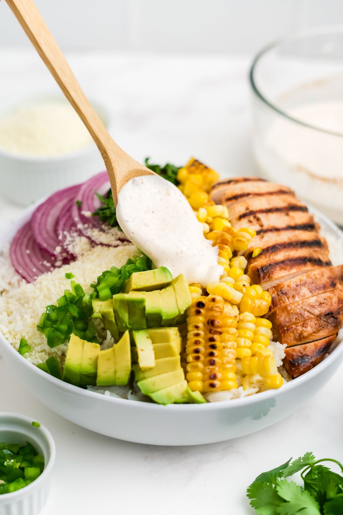 Dressing being drizzled on a meal bowl. 